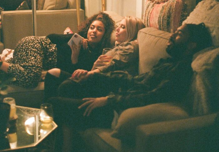 Friends relaxing on a couch, laughing and chatting, creating a cozy atmosphere.