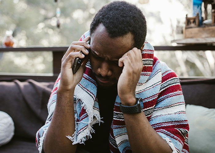 Man looking confused while on a phone call, wrapped in a striped blanket, outdoors. Man looking confused while on a phone call, wrapped in a striped blanket, outdoors.