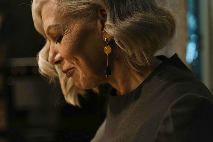 Elderly woman with stylish earrings, side profile.