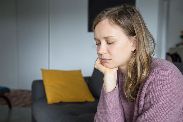 A woman in a purple sweater looks thoughtful while sitting on a couch, relating to self-described ugly man standards. A woman in a purple sweater looks thoughtful while sitting on a couch, relating to self-described ugly man standards.