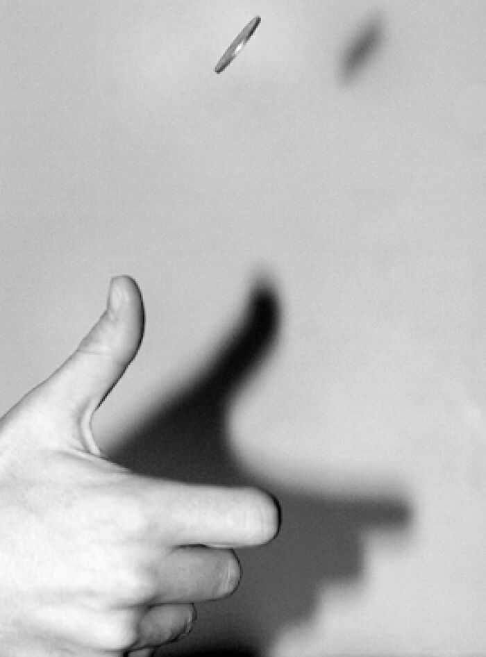 Hand flipping a coin in black and white, symbolizing last-minute decisions that changed the course of history.