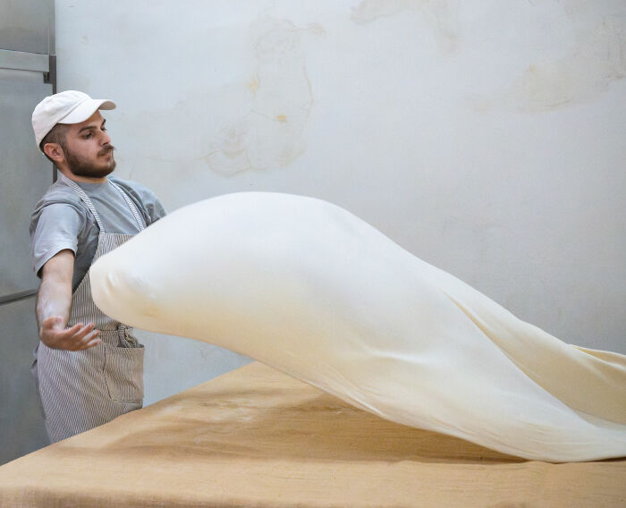 Man expertly stretching dough in bakery, showcasing a shortlisted entry for the 2025 World Food Photography Awards.