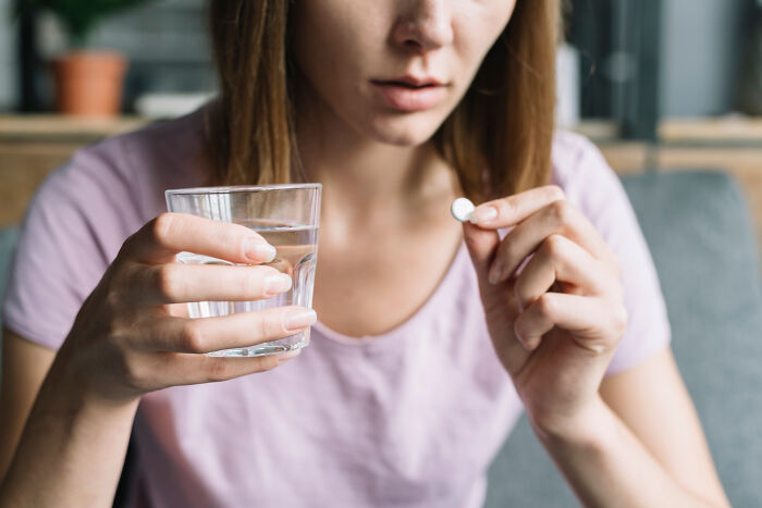 Woman holding a glass of water and a pill, representing overlooked science findings.