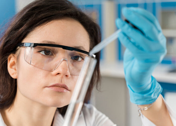 Student in science lab with safety goggles and gloves, conducting an experiment related to high school incidents.