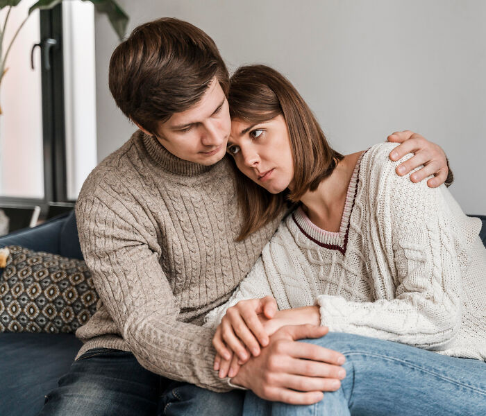 Couple sitting closely on a couch, wearing cozy sweaters, addressing common assumptions about women.