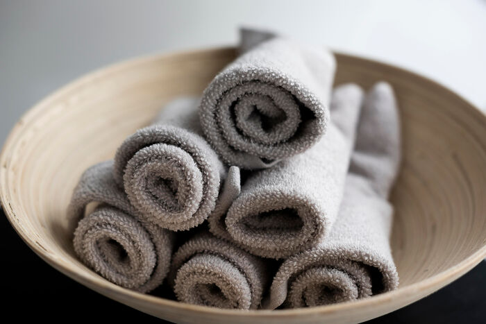 Gray rolled towels in a wooden bowl, resembling an affordable yet fancy treat display.