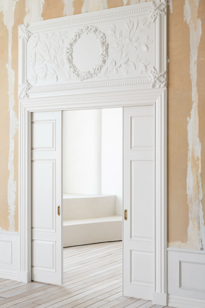 Elegant white sliding door with decorative molding, not practical for all homes.