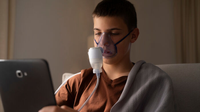 A person using a nebulizer while looking at a tablet, highlighting overlooked science.