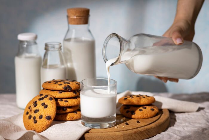 Assortment of milk bottles and chocolate chip cookies on a table, emphasizing bizarre house rules.