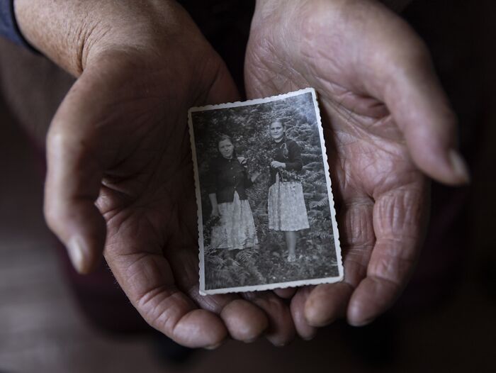 Hands holding a vintage photo, symbolizing the vulnerability of aging women.