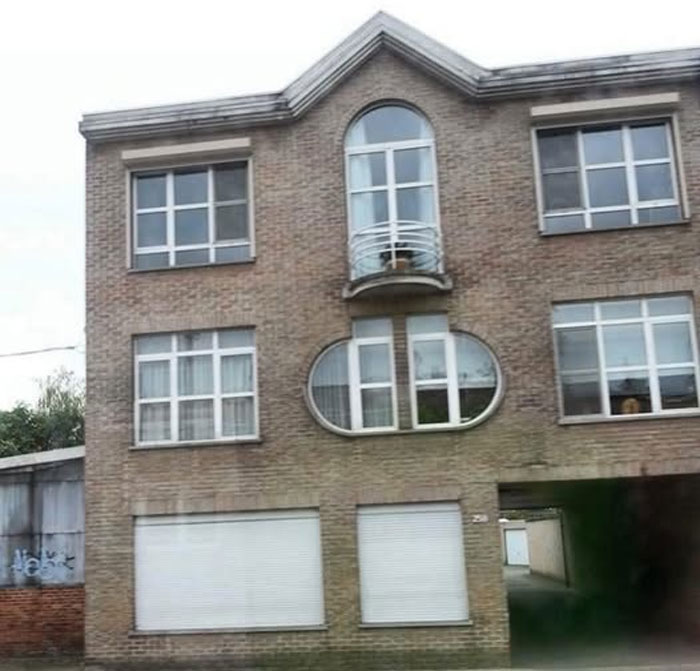 Unusual real estate property with unique oval and arched windows on a brick building for sale in an urban area.