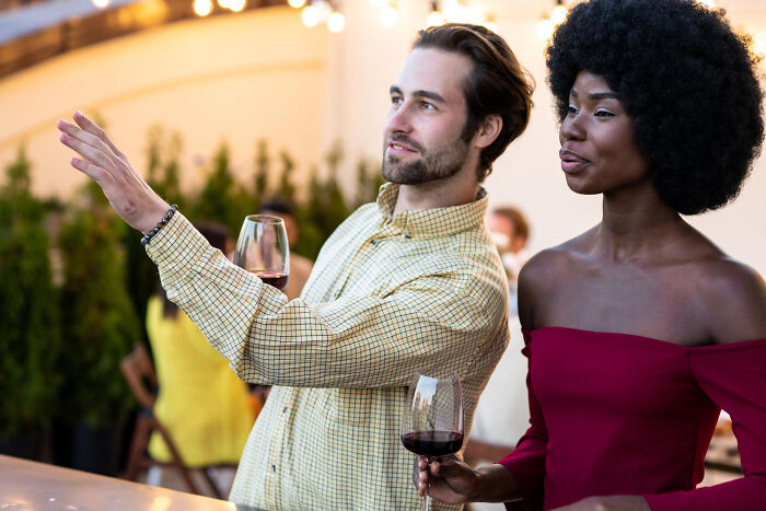 A man and woman holding wine glasses enjoying an outdoor evening gathering, illustrating a super normal thing country lifestyle.