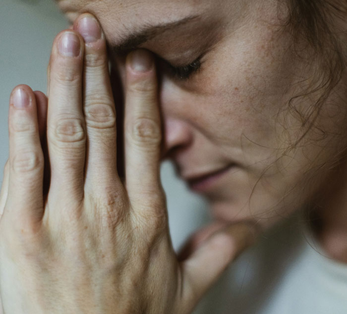 Close-up of a distressed woman with her hands on her face, emphasizing emotion and tension.