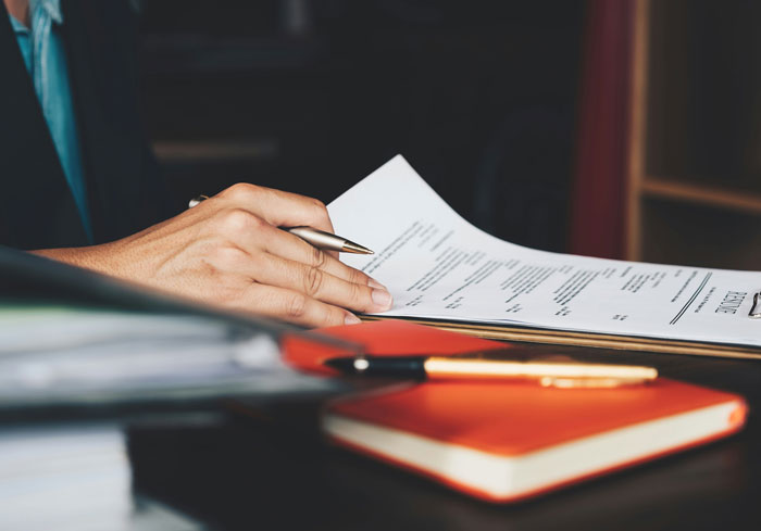 Person reviewing a resume with a pen, focused on job hunting tips.