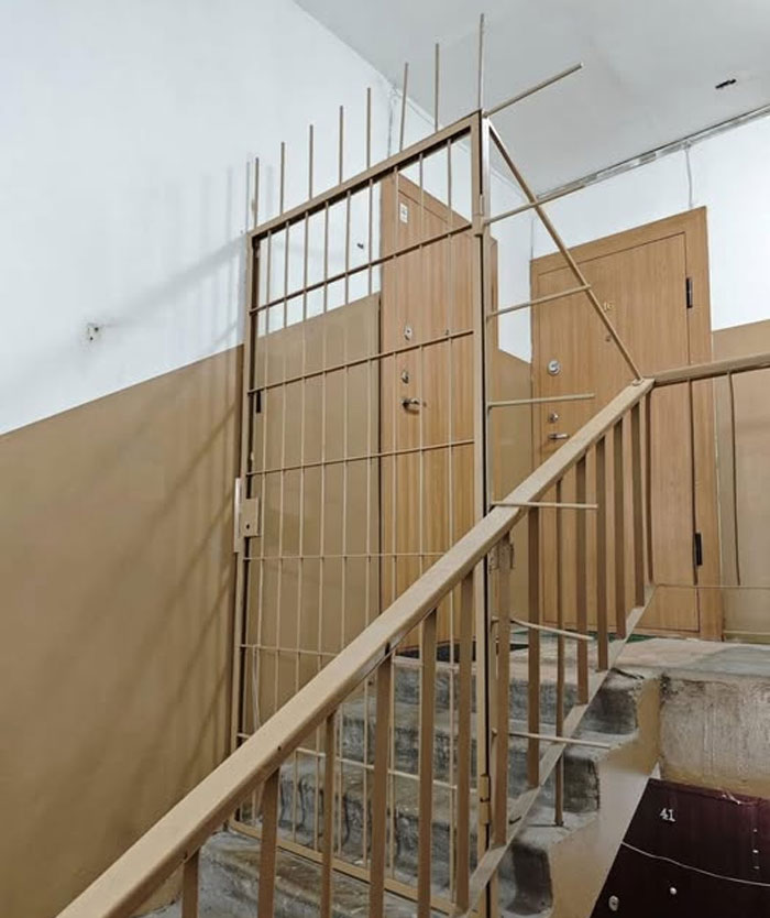 Beige stairwell with metal gate and wooden doors, showcasing one of the wildest real estate properties for sale.