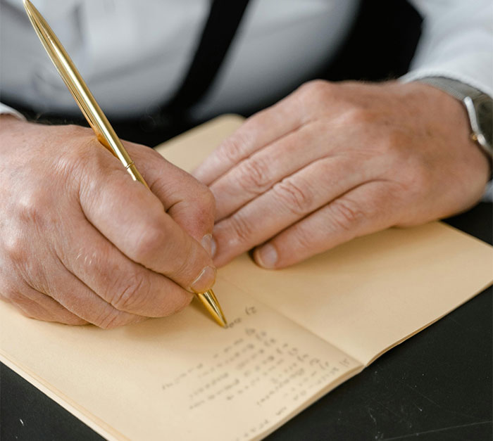 A person writing in a notebook, highlighting a story about close parent relationships, using a gold pen.