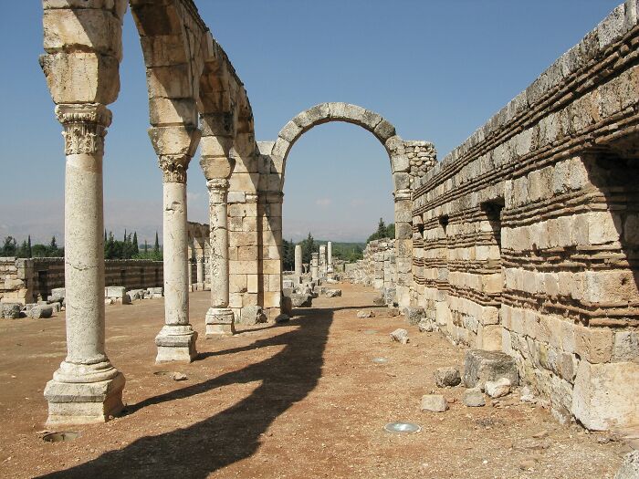 Ancient stone arches in a lesser-known architectural wonder, with columns casting shadows on a clear day.