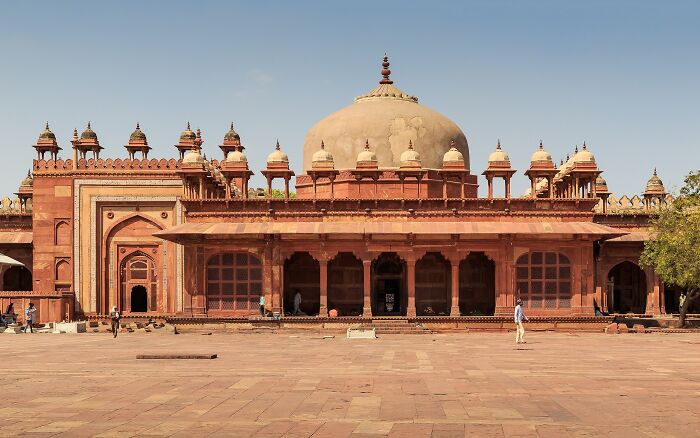 Unrecognized architectural wonder featuring intricate red stonework and domes under a clear blue sky.