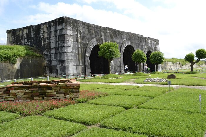 Ancient architectural wonder with stone arches, surrounded by greenery and pathways.