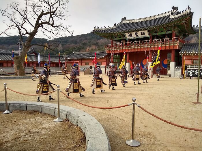 Traditional soldiers in front of an architectural wonder with ornate carvings and banners, showcasing cultural heritage.