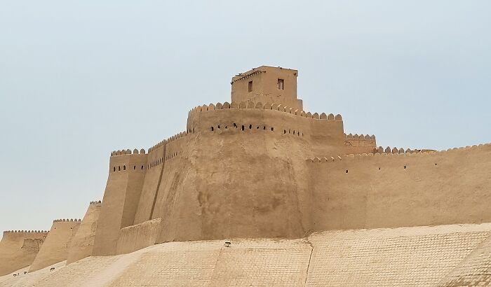 Ancient architectural wonder with massive clay walls and a central tower, showcasing historical craftsmanship against a clear sky.
