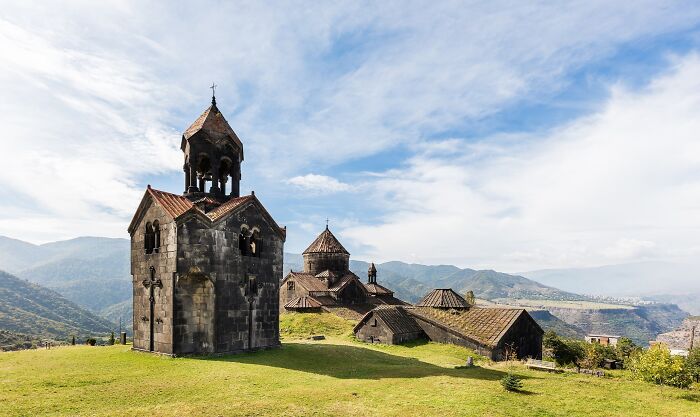 Ancient stone church on a hill with mountains in the background, representing architectural wonders not well-known.
