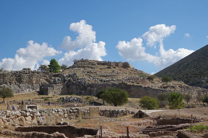 Ancient architectural wonder featuring rustic stone ruins under a clear blue sky with scattered clouds.