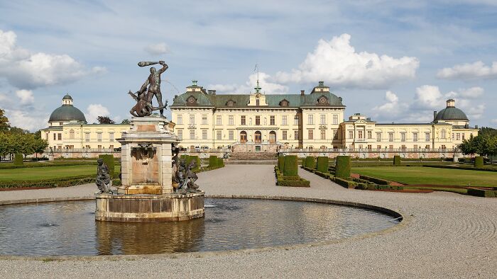 A grand, lesser-known architectural wonder with a classical facade and ornate fountain under a blue sky.