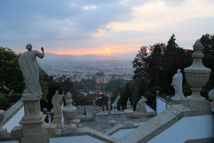 Stone statues overlooking a cityscape at sunset, showcasing lesser-known architectural wonders.