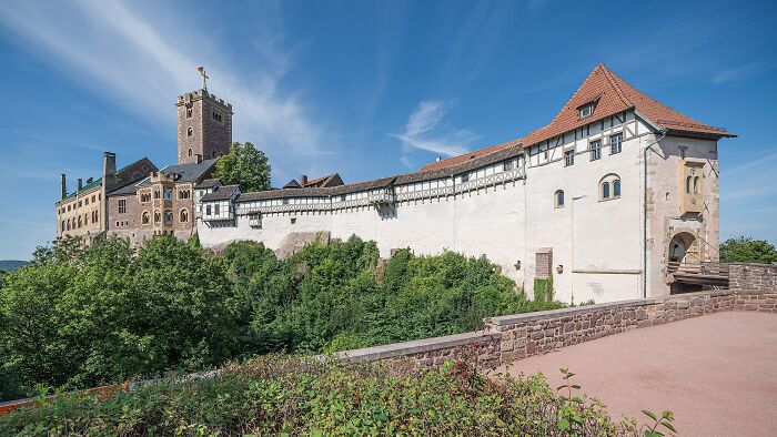 Historic architectural wonder featuring a stone tower and walls surrounded by lush greenery under a blue sky.