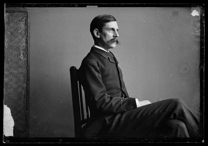 Black and white rare photograph of a man with a mustache in vintage suit, seated in profile, rescued from glass negatives.