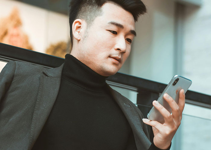 Young man looking at phone with a concerned expression, reflecting on heartbroken people revealing cheating signs.