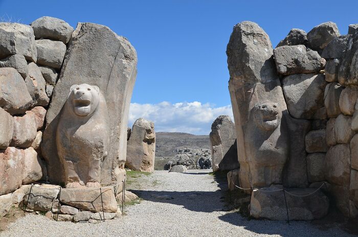 Ancient stone lion gate, an architectural wonder, with sculpted lion figures under a clear blue sky.