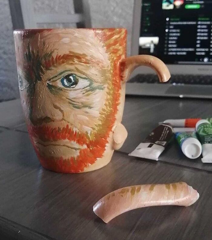 A mug painted with a face and a broken handle, depicting a relatable meme scenario.