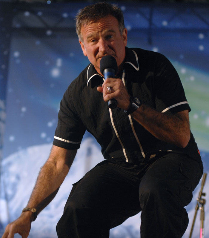 A performer in a black shirt holding a microphone, engaging with the audience on stage.