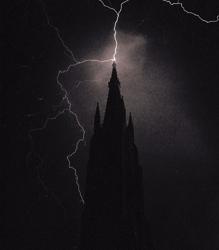 Gothic spire silhouetted against a stormy sky with lightning. Dreamy dark escapism photography.