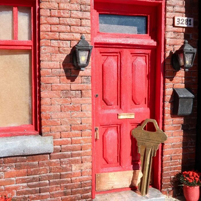Miniature red door with oversized key, showcasing Tamar Cohen's tiny worlds artistry.