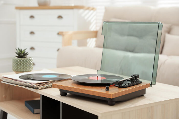 Turntable with vinyl records on a stylish coffee table, highlighting an affordable treat with a fancy feel.