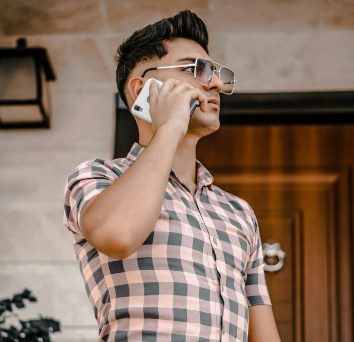 Man in checkered shirt talking on smartphone in front of a door, illustrating close parental relationships theme.