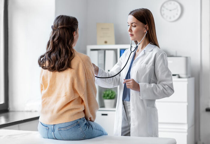 A doctor uses a stethoscope on a patient in a medical office, illustrating a common American healthcare practice.