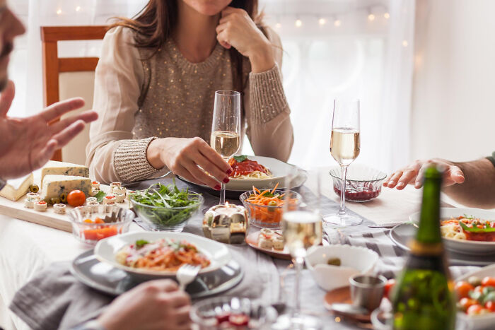 People enjoying a super normal thing country meal with pasta, wine, and fresh salads in a cozy dining setting.