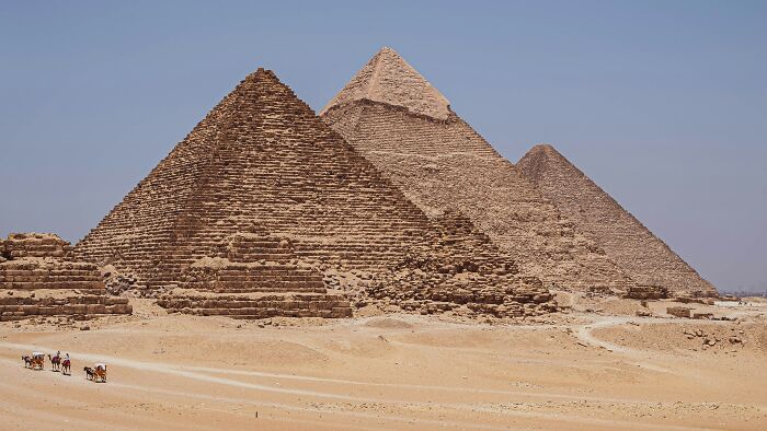 Three ancient man-made structures in Egypt known as the pyramids standing in a desert landscape.
