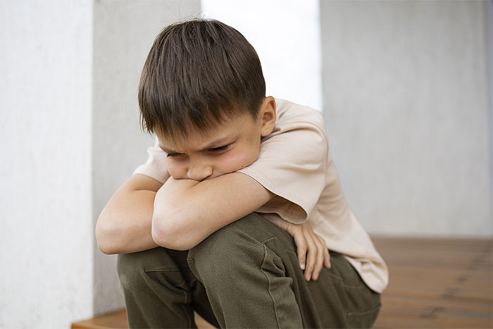 Child sitting on a porch, appearing upset, representing babysitting miscommunication impacts.