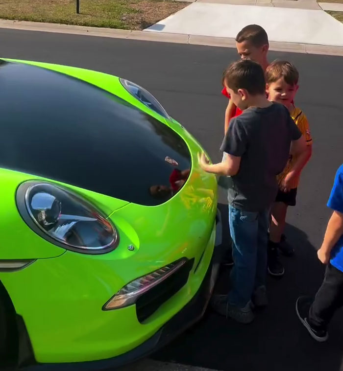 Children admiring a bright green sports car parked on the street.