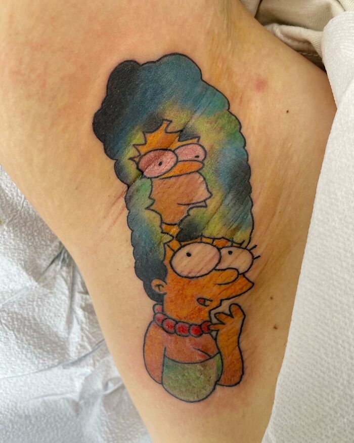 Simpsons tattoo with Marge and Bart in vivid colors on arm.