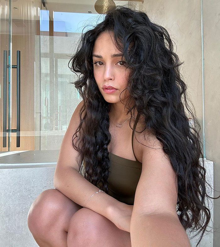 Streamer posing indoors with long curly hair, wearing a green top, linked to 'Minecraft' scene controversy.