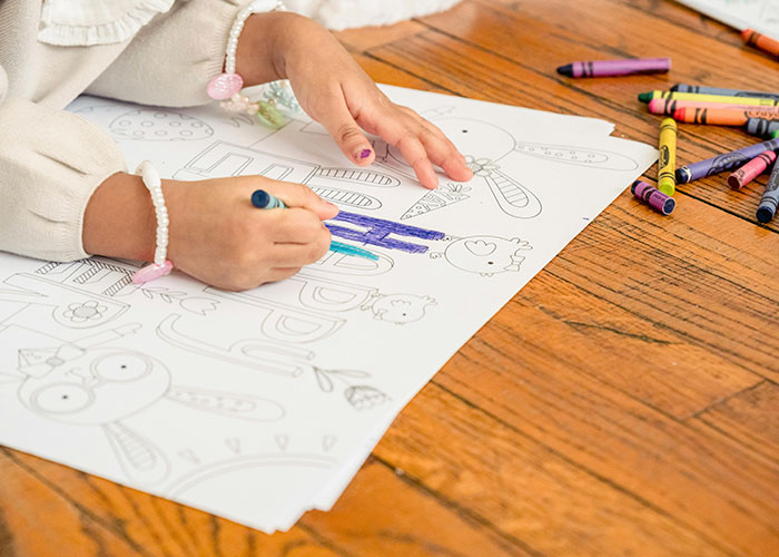 Child coloring on the floor with crayons scattered, illustrating creative play.