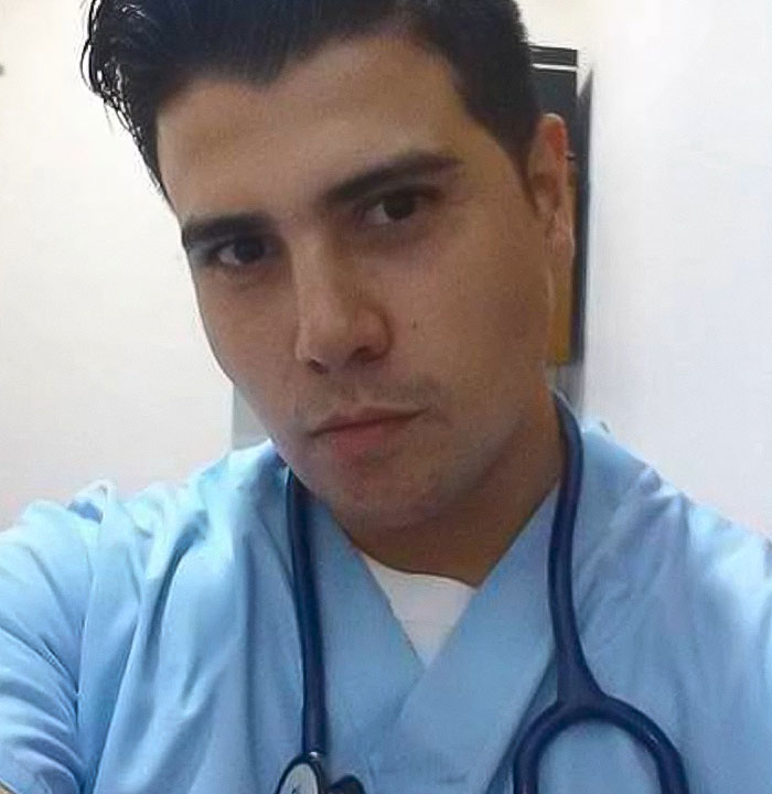 Young man in medical attire with stethoscope, posing as plastic surgeon.