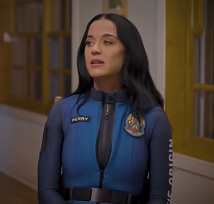 Woman in a Blue Origin jumpsuit, seated indoors, sparking conspiracy theories.