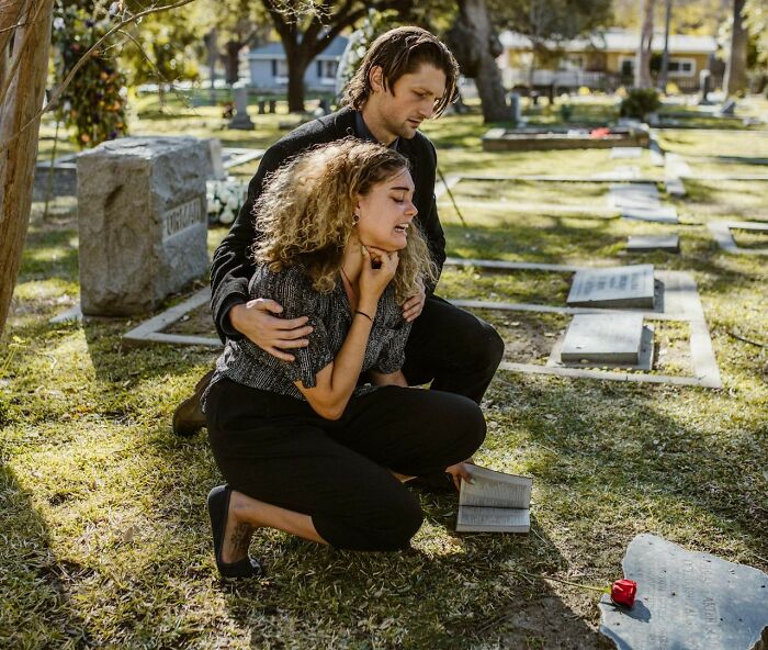 Woman comforted by man at cemetery, emphasizing disparities in pain meds prescriptions.